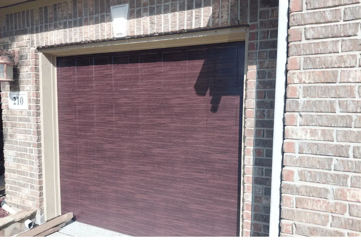 Stamped shaker-style garage door with a painted wood-tone finish